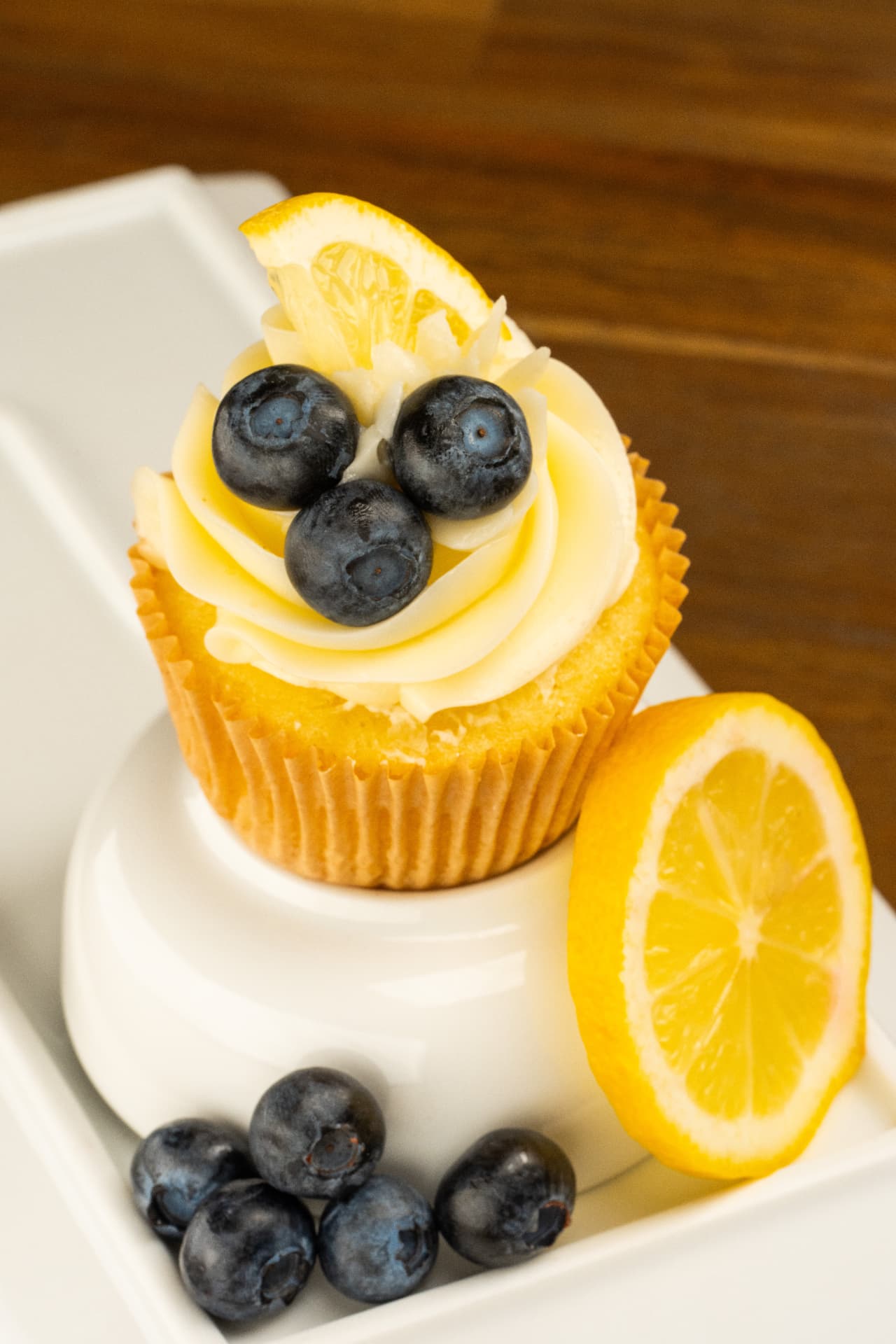 Overhead view of a lemon blueberry cupcake with white chocolate curls and a lemon wedge